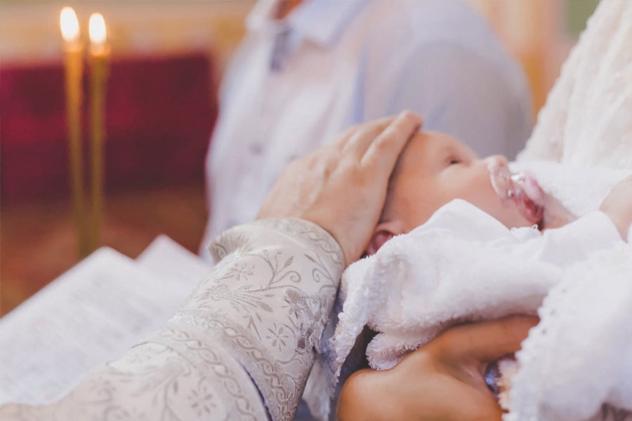 A baby being blessed by a priest